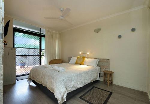 a bedroom with a bed and a large window at Beach at your feet in Bargara