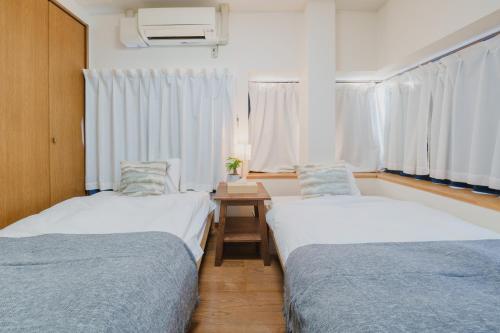 掛川市にあるWhite Spaceのベッド2台、テーブル、窓が備わる客室です。