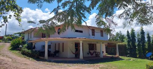 Una casa blanca con un árbol delante. en Casa completa/ familiar a 3km de playa el Arenal en Pedasí Town