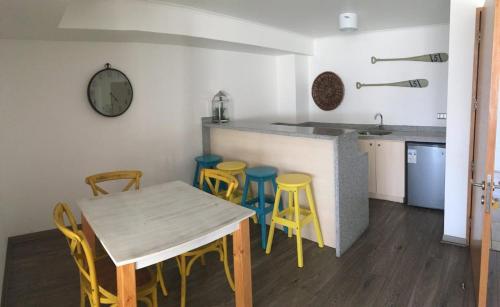 a kitchen with a table and some yellow stools at Departamento Aqua La Serena in La Serena