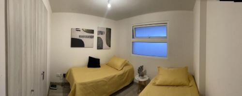 a bedroom with two beds and a window at Departamento Aqua La Serena in La Serena