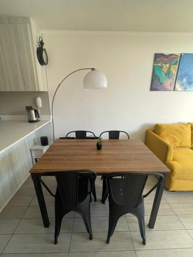 a dining room table with chairs and a yellow couch at Departamento Aqua La Serena in La Serena