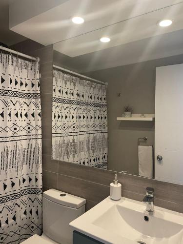 a bathroom with a toilet and a sink and a mirror at Departamento Aqua La Serena in La Serena