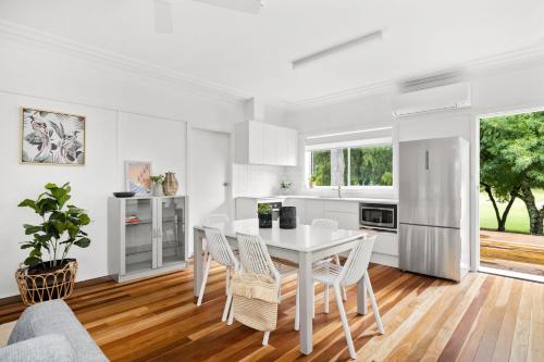 a white kitchen with a white table and chairs at Barefoot Bungalow in Mollymook
