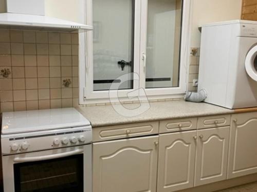 une cuisine avec des armoires blanches, un évier et un micro-ondes dans l'établissement Maison familiale avec jardin, proche plages et WIFI - FR-1-357-89, à La Jonchère