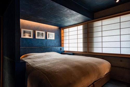 a bedroom with a large bed in a room with windows at DELTA Stay in Kyoto