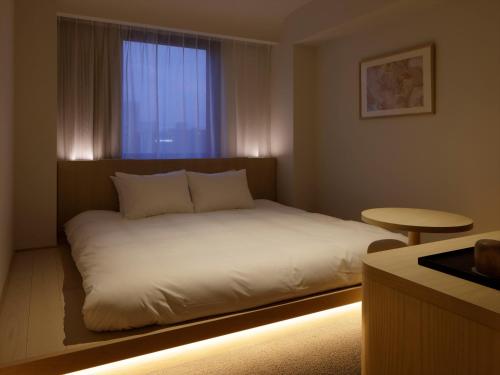 a bedroom with a bed with a window and a table at SOKI Kanazawa in Kanazawa