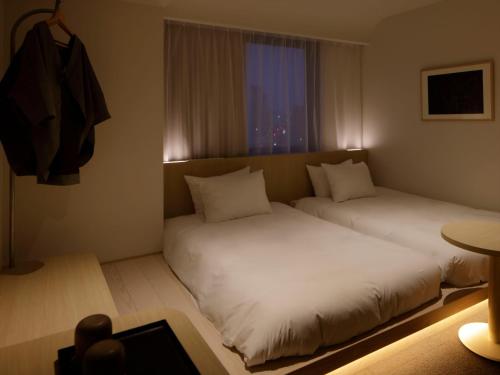 two beds in a small room with a window at SOKI Kanazawa in Kanazawa