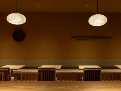 a dining room with tables and chairs and lights at SOKI Kanazawa in Kanazawa