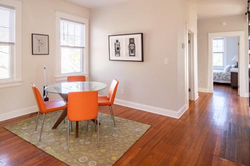 a dining room with a glass table and orange chairs at Contemporary 3-Bedroom Home with Balcony in RVA in Richmond
