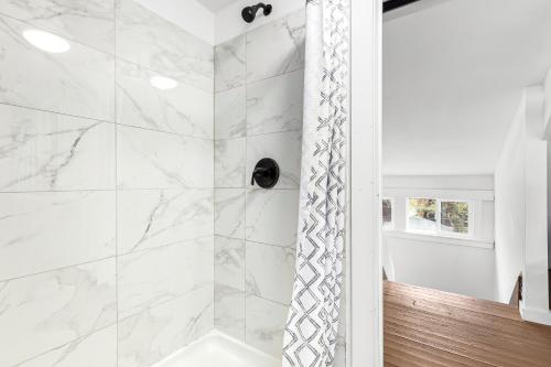 a bathroom with a shower with white marble walls at Stately Studio Apartment in Detroit