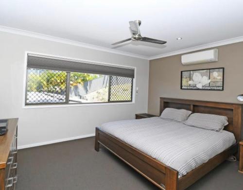 a bedroom with a bed and a window at Two Storey Beach House in Hervey Bay