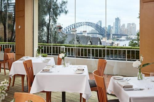 un restaurant avec des tables et des chaises et une vue sur le port de Sydney. dans l'établissement View Sydney, à Sydney