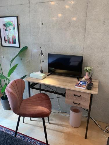 a desk with a television and a chair in a room at Ken's Place四谷 in Tokyo