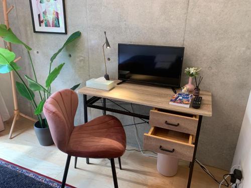 a desk with a television and a chair in a room at Ken's Place四谷 in Tokyo