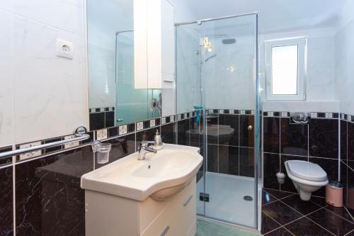 La salle de bains est pourvue de toilettes, d'un lavabo et d'une douche. dans l'établissement Apartments Dream view, à Brela