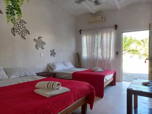 a bedroom with two beds with red sheets and a window at Camino al Mar in Ipala