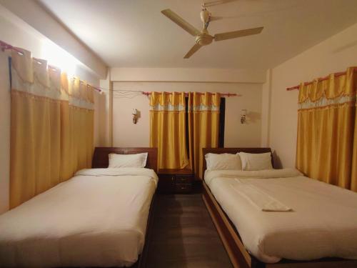 two beds in a room with yellow curtains at Hotel Town View in Sauraha