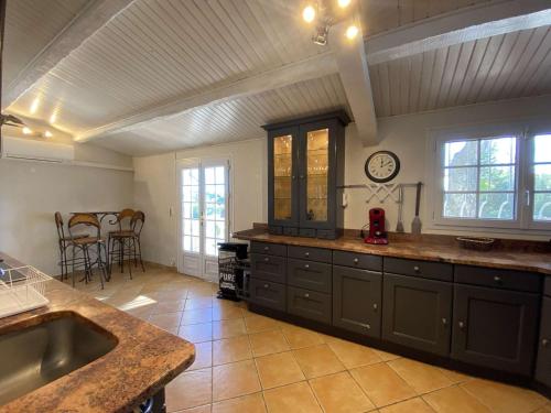 une grande cuisine avec un évier et une horloge murale. dans l'établissement Villa de Charme 5 Pièces avec Piscine Privée, Jardin Arboré, Proche Plage et Centre-ville - FR-1-226-501, à Sainte-Maxime