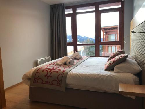 sypialnia z psem leżącym na łóżku z oknem w obiekcie Appartement spacieux avec parking, balcon et accès piscine - Front de neige - FR-1-346-536 w mieście Arc 1800