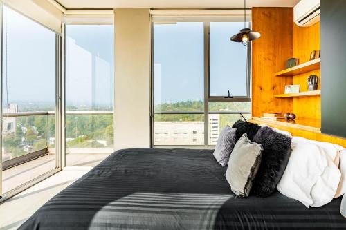 a bedroom with a large bed with large windows at Departamento con las mejores vistas de la ciudad en Condesa - pool - gym - parking - AC in Mexico City