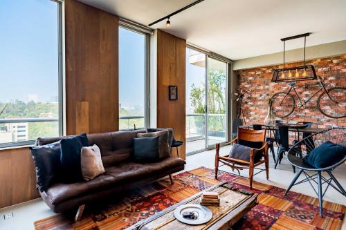 a living room with a leather couch and a brick wall at Departamento con las mejores vistas de la ciudad en Condesa - pool - gym - parking - AC in Mexico City