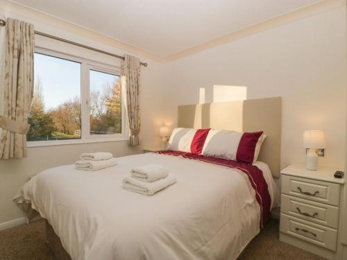 a bedroom with a white bed with towels on it at Bramley Lodge in Puxton
