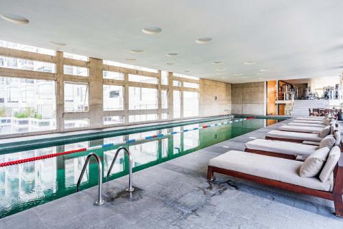a swimming pool with a row of chairs next to it at Departamento con las mejores vistas de la ciudad en Condesa - pool - gym - parking - AC in Mexico City