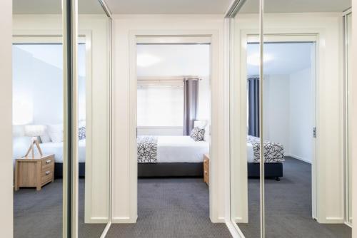 a bedroom with two beds and two mirrors at Warners Bay Apartments in Warners Bay