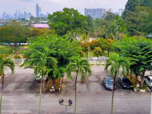 een parkeerplaats met geparkeerde auto's en palmbomen bij Pusat Belia Antarabangsa in Kuala Lumpur