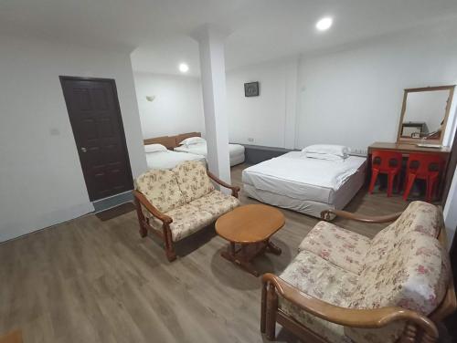 een kamer met 2 bedden, 2 stoelen en een tafel bij OYO 90809 Oriental Hotel in Sarikei