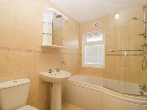 a bathroom with a sink and a toilet and a tub at Blenheim Lodge in Puxton