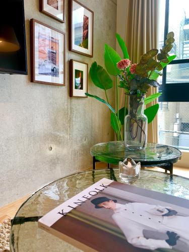 a glass table with a vase of flowers on top of it at Ken's Place四谷 in Tokyo