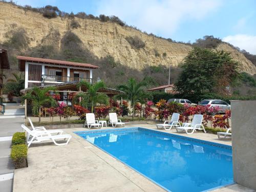 un complexe avec une piscine, des chaises et une montagne dans l'établissement Canoa South Beach, à Canoa