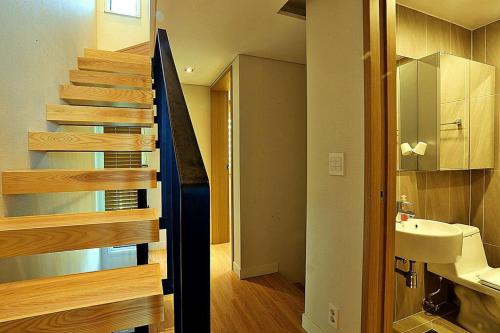 a bathroom with a sink and a staircase in a house at Coveted Palms Village Pension in Jeju