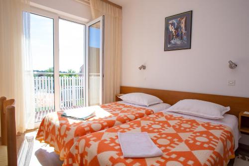 a bedroom with two beds and a large window at Apartments and rooms Ivan - great location in Novalja