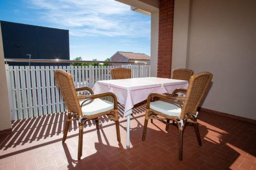 een tafel en stoelen op een balkon met een witte tafel en stoelen bij Apartments and rooms Ivan - great location in Novalja