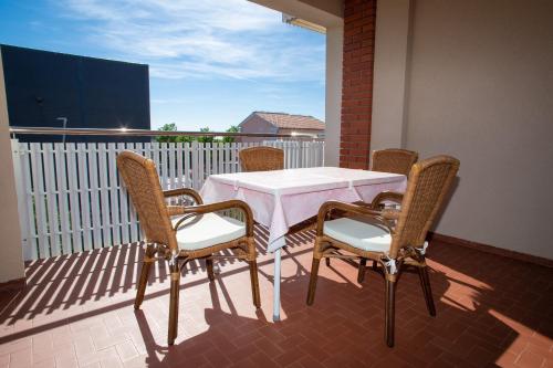 a table and chairs on a balcony with a white table and chairs at Apartments and rooms Ivan - great location in Novalja