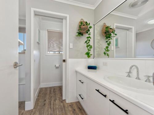 a white bathroom with a sink and a mirror at 242 Woongarra Scenic Drive in Bargara