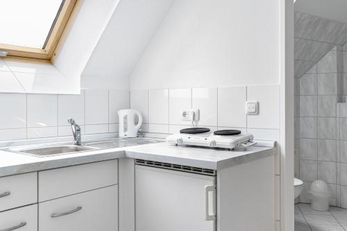 a white kitchen with a stove and a sink at Löwen Pension in Unterlüß