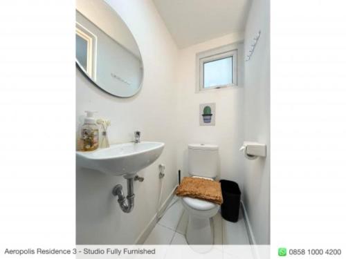 een badkamer met een wastafel, een toilet en een spiegel bij Aeropolis Near TOD M1 in Teko