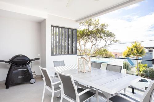 a white dining room with a white table and chairs at Ohana On Hungerford in Kingscliff