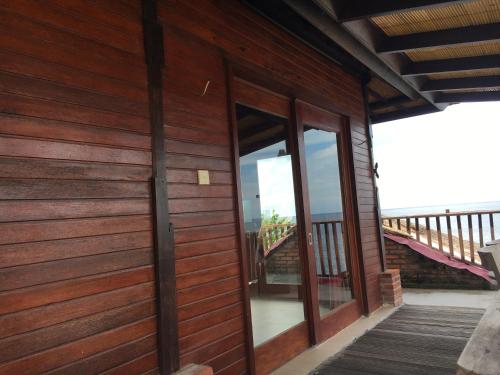 a wooden house with glass doors and a balcony at Amed Sunset Beach in Amed