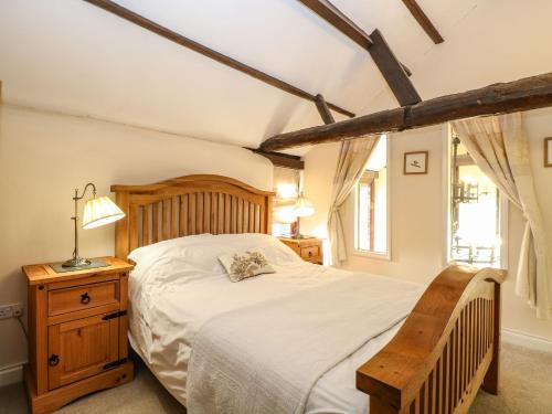 a bedroom with a wooden bed and a wooden chair at The Barn in Ashill
