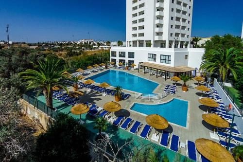 a swimming pool with umbrellas and chairs and a building at Penthouse Rentalbufeira in Albufeira