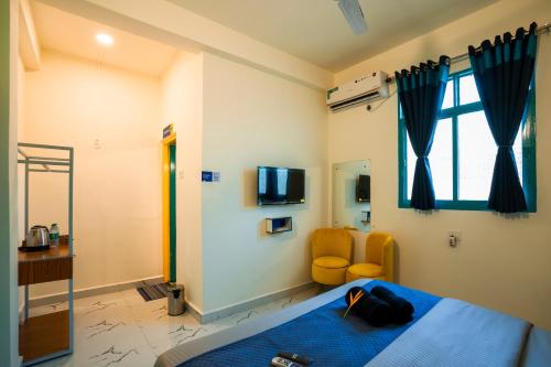 a bedroom with a bed and a tv and a chair at Shalom Backpackers Anjuna Goa in Anjuna
