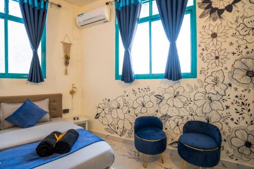 a bedroom with a bed and two blue chairs at Shalom Backpackers Anjuna Goa in Anjuna