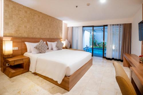 a bedroom with a large bed and a large window at Cross Vibe Paasha Atelier Bali Kuta in Kuta