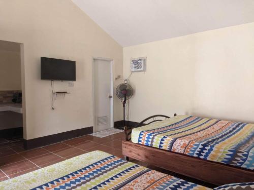 a bedroom with two beds and a flat screen tv at Miguel's Homestay in Pañge