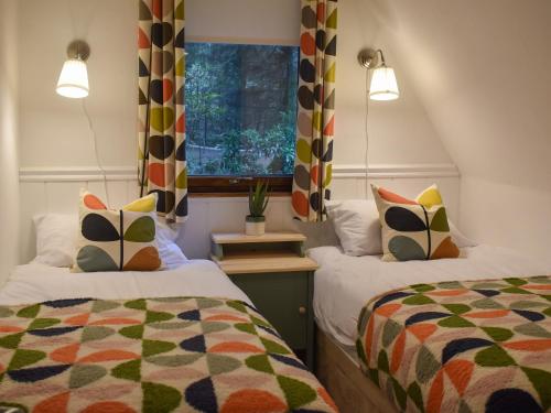 a small room with two beds and a window at Pine Needle Lodge in Kilfinnan